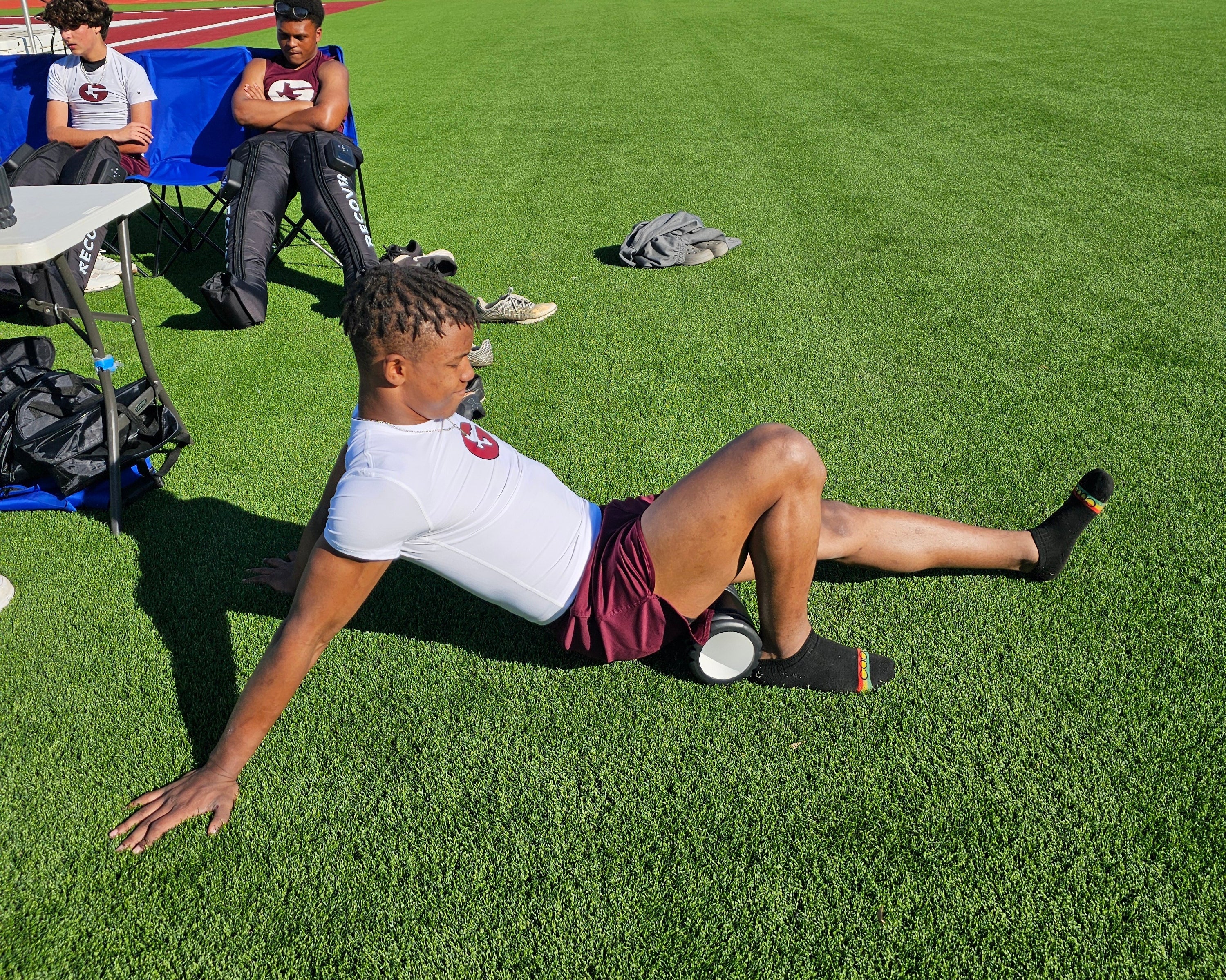 Person lying on a grassy field with sports equipment around
